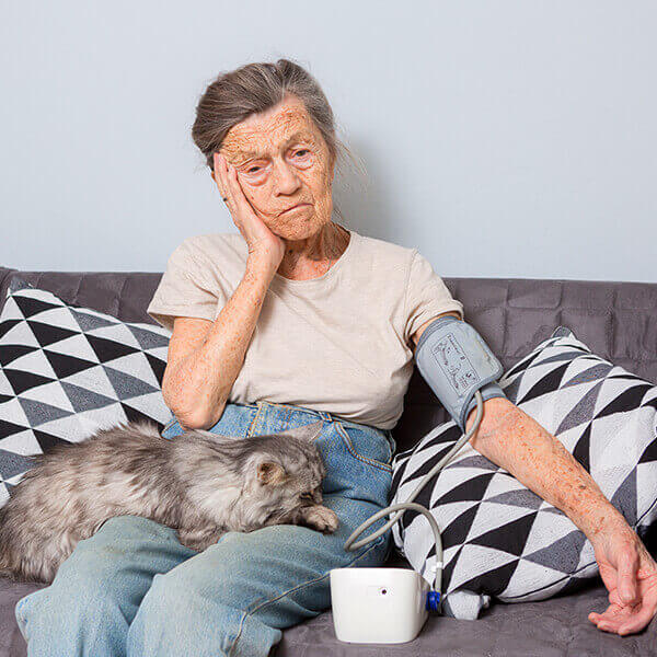 Elderly lady taking her blood pressure with pet cat