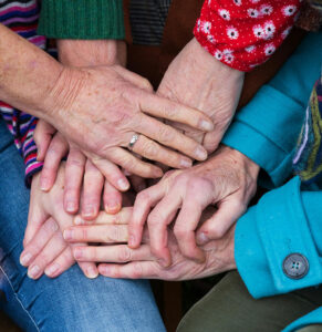 Close-up of elderly and younger hands stacked together in a show of love, unity, and multi-generational support.