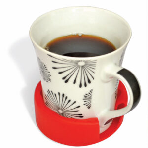 White ceramic mug with a black and floral pattern placed inside a red silicone cup holder for improved stability and grip.