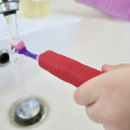 T-PCG-R-Red-Childrens-Cutlery-Grips-Girl-Holding-Toothbrush-Under-Tap-2