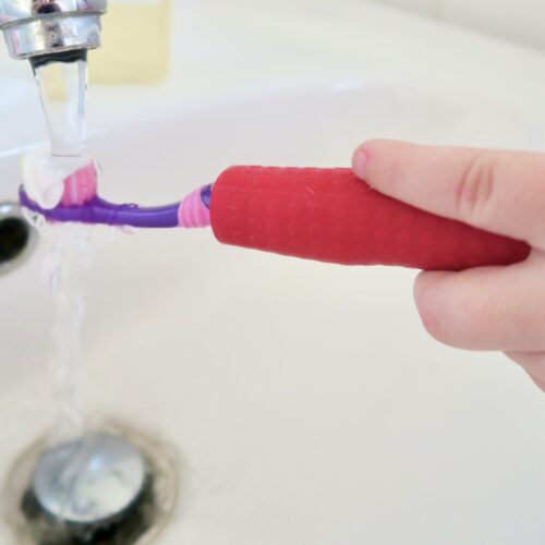 T-PCG-R-Red-Childrens-Cutlery-Grips-Girl-Holding-Toothbrush-Under-Tap-3